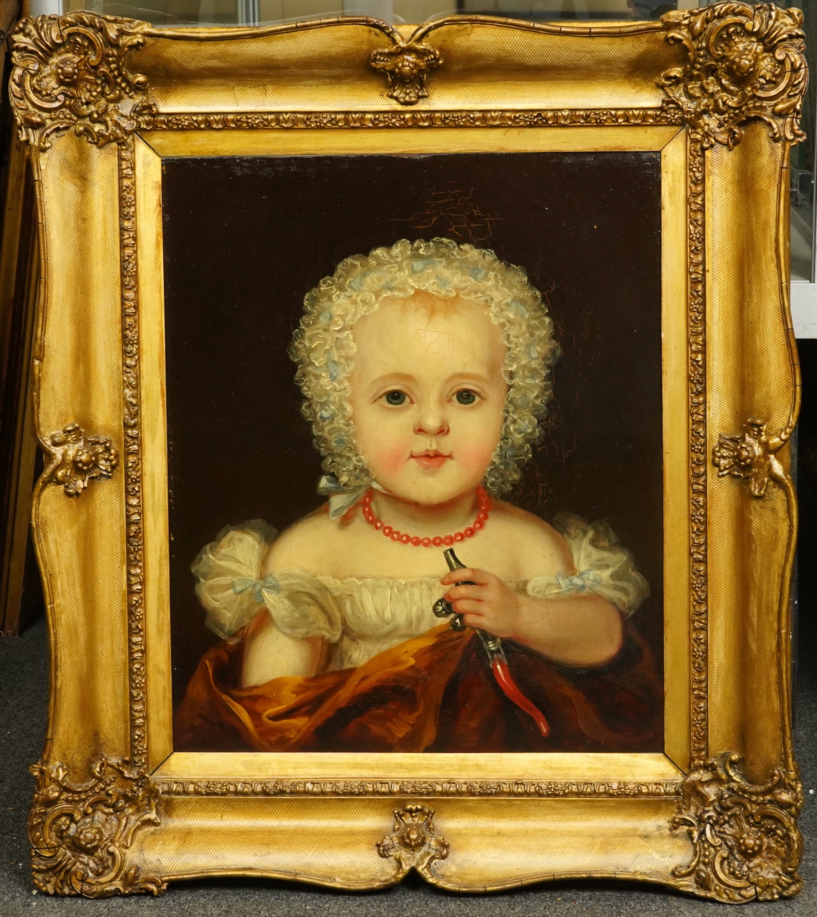 English School c.1840 , Portrait of an infant wearing a coral necklace and holding a silver rattle, oil on board, 42 x 35cm